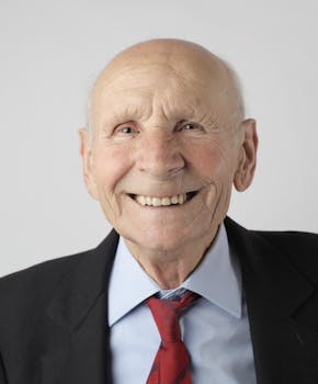 A joyful elderly man in a suit and tie smiles warmly. Perfect for senior lifestyle themes.