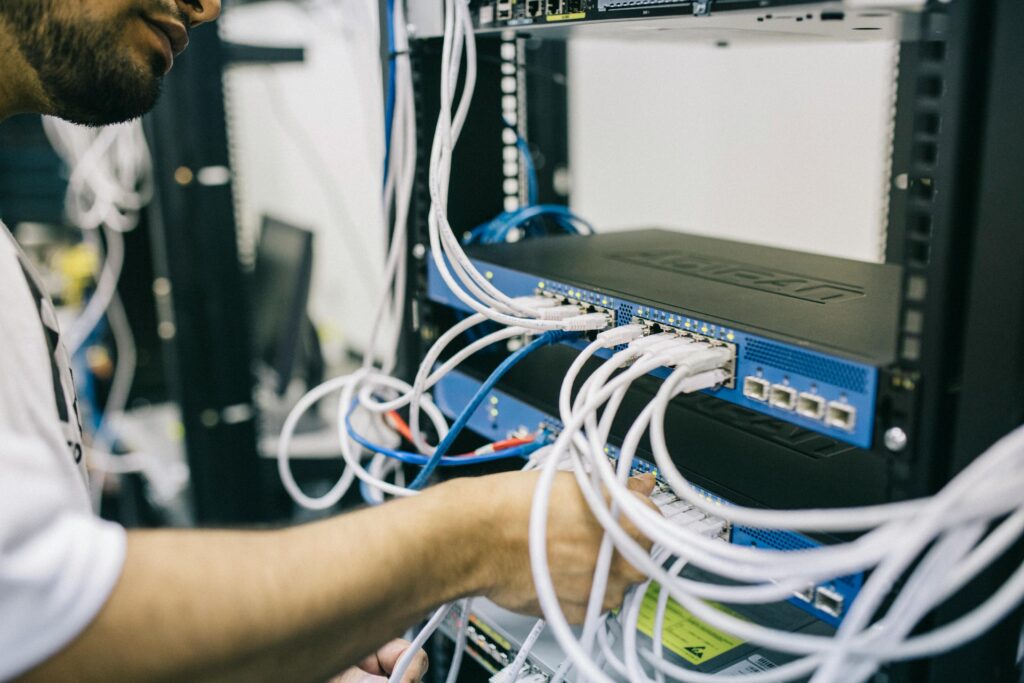 pexels photo 442150 442150 An IT professional configuring network cables in a server rack, focusing on Ethernet connections.